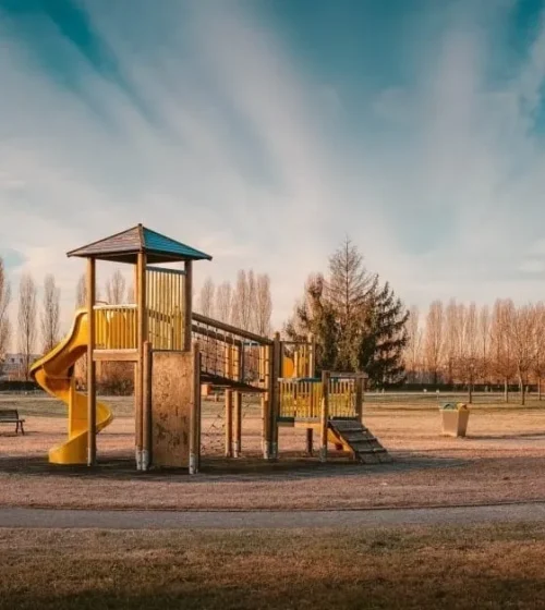 Modular playground structure with yellow slide in an open park setting.