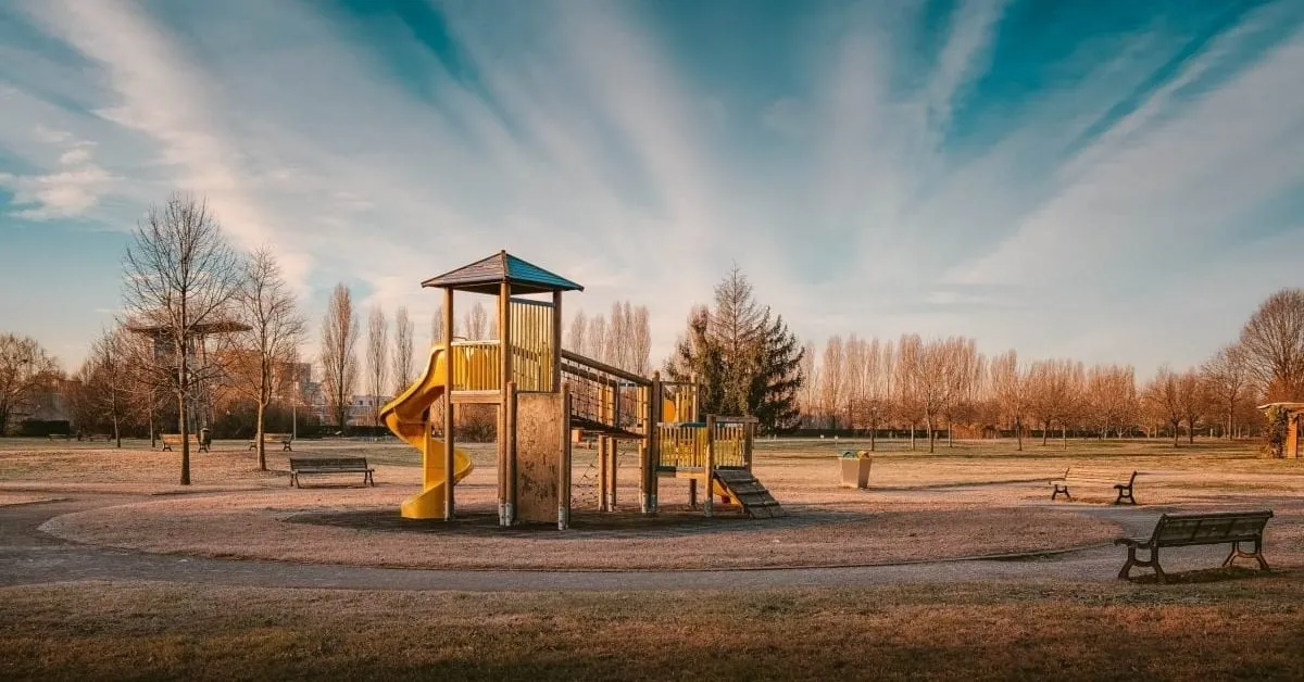 Modular playground structure with yellow slide in an open park setting.