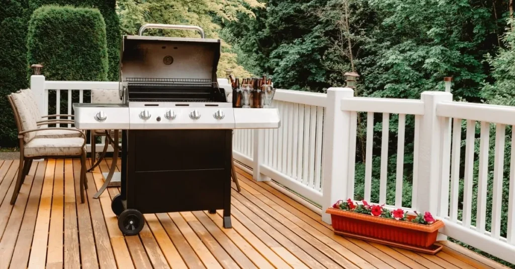 A stylish outdoor deck featuring a modern grill, comfortable seating, and lush greenery, creating an inviting space for gatherings.