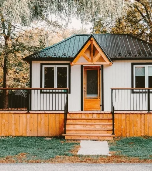 Cozy wooden deck surrounding a small cottage.