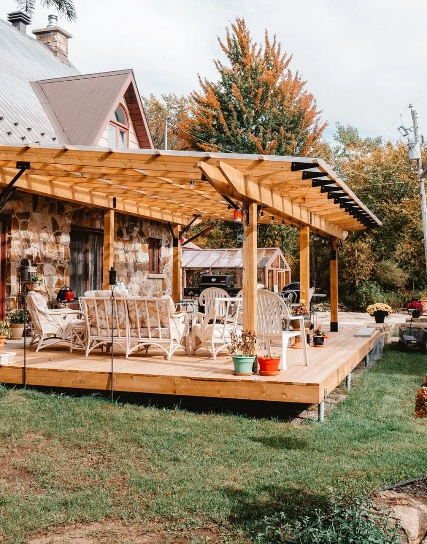 Wooden deck with pergola and cozy outdoor seating.