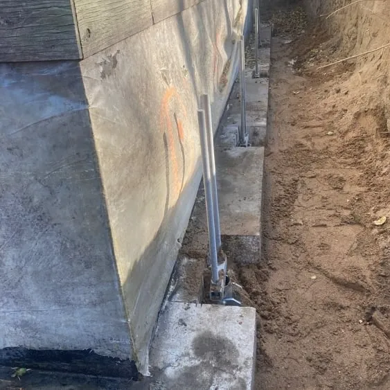 Close-up of adjustable screw pile heads installed along a concrete foundation for precise leveling and support.