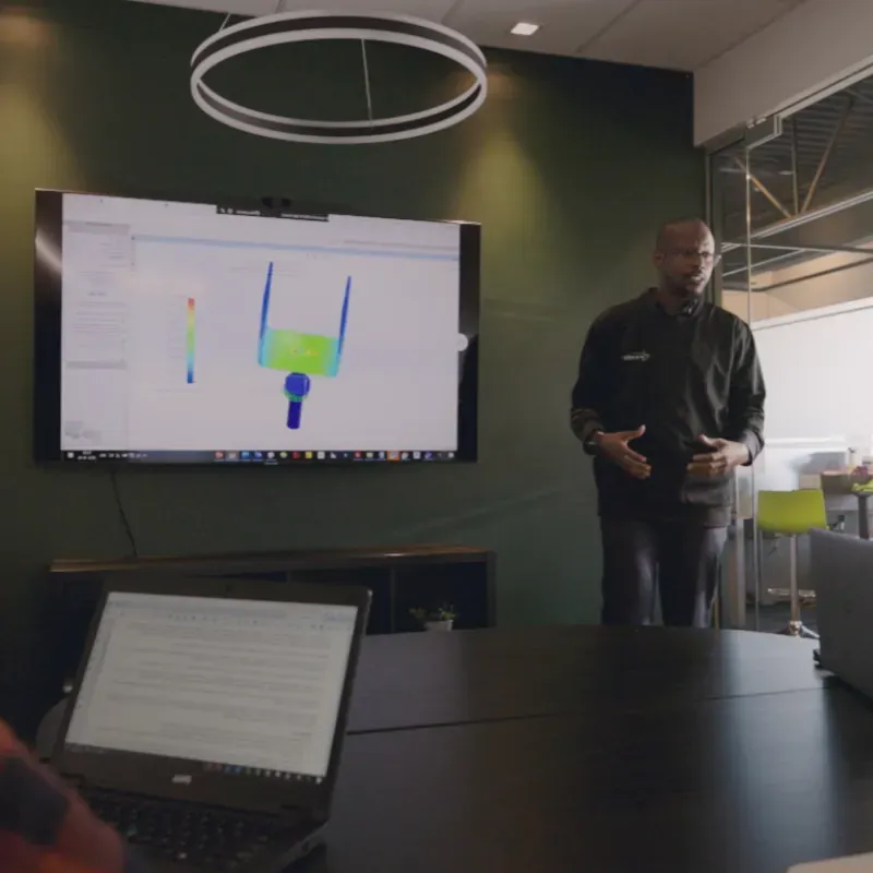 Engineer giving a presentation in a modern office, showcasing a 3D model of a technical design on a screen.