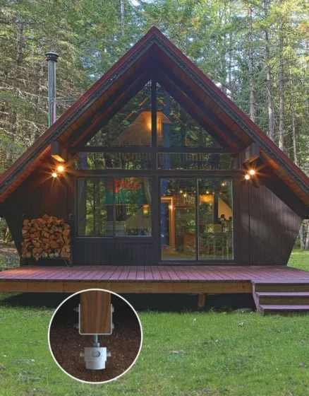 A cozy cabin nestled in the forest with a wooden deck, supported by durable screw pile foundations for stability.